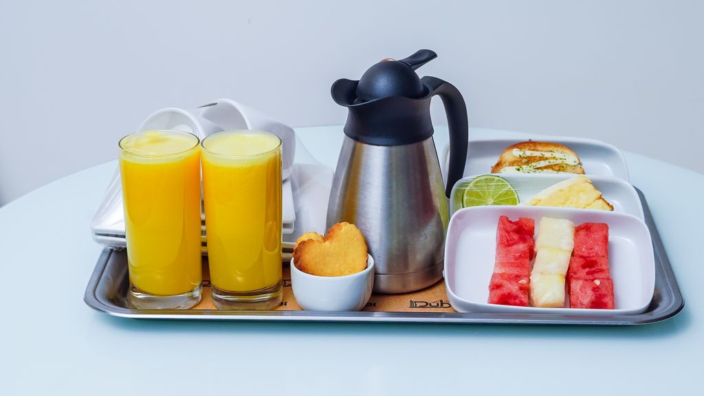 A breakfast tray with orange juice, pastries, and fresh fruits, perfect for a balanced meal.